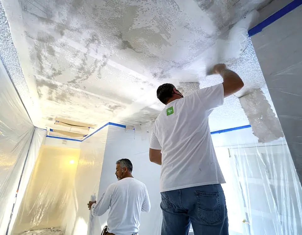Handyman performing drywall repair and interior painting preparation